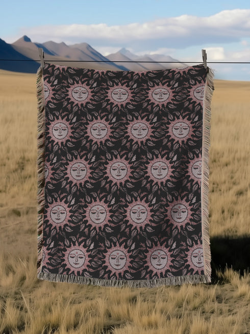 Luxurious woven cotton throw featuring dreamy blush pink sun faces with closed eyes against black background with delicate ray patterns and elegant fringe trim. Perfect celestial wall hanging, witchy bedroom decor, or dark academia throw blanket.